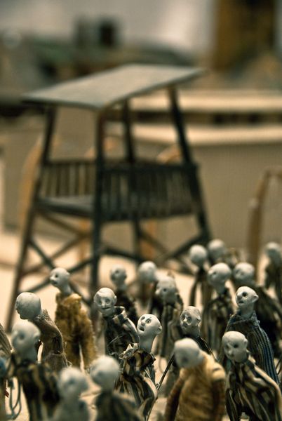 Een miniatuurwachttoren steekt boven een menigte kleine poppetjes uit.