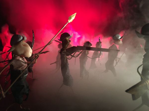 Gewapende figuurtjes met speren en bogen komen door de rook naar voren, met een felrode gloed achter hen.