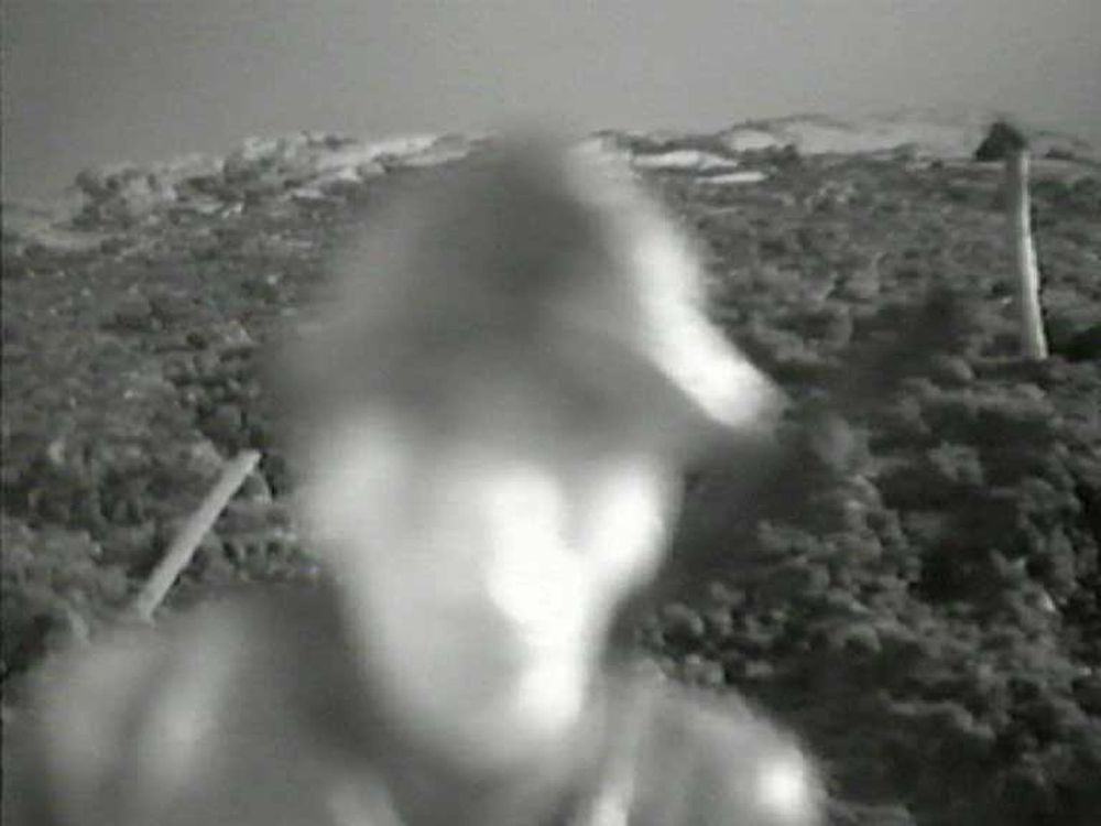 Zwart-wit: het onscherpe gezicht van een soldaat komt van dichtbij op de camera af, met het lege landschap erachter.
