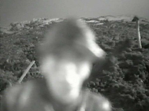 Zwart-wit: het onscherpe gezicht van een soldaat komt van dichtbij op de camera af, met het lege landschap erachter.