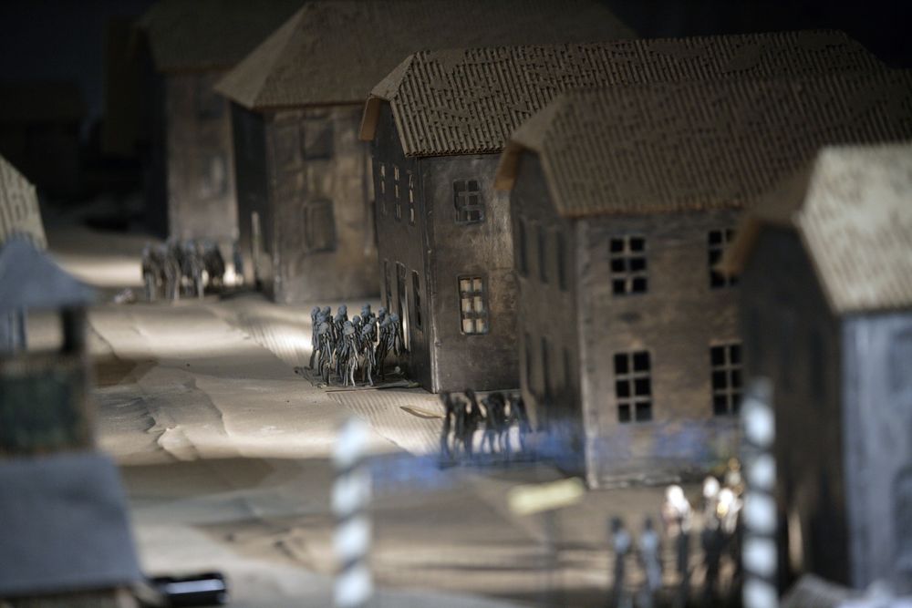 Een straat met bakstenen barakken in de maquette; ertussen lopen kleine groepjes poppetjes.