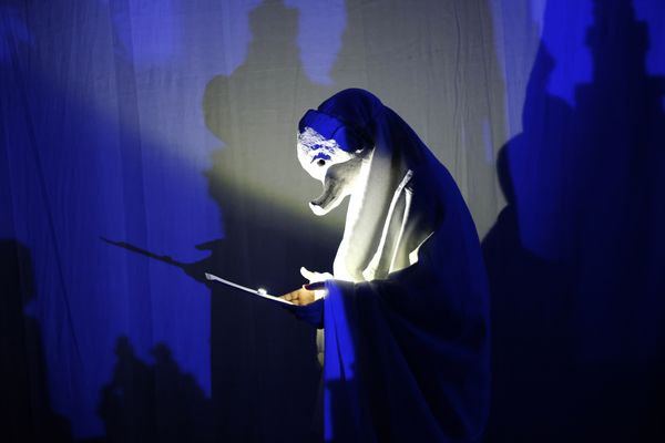 gemaskerd figuur leest brief in blauw schijnsel