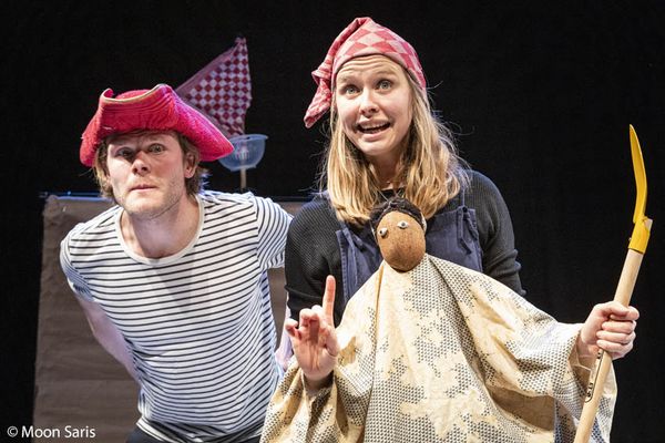 Twee spelers met piratenhoed en hoofddoek staan naast elkaar; zij houdt een pop met een geel zwaard in haar arm.